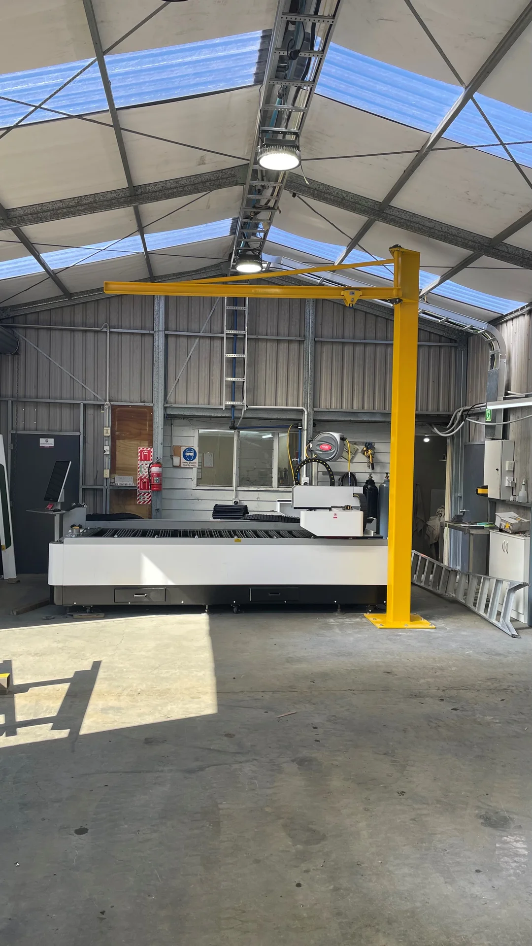 The laser cutter inside the AMC Engineering Ltd Waipukurau workshop, with a yellow jib crane beside it