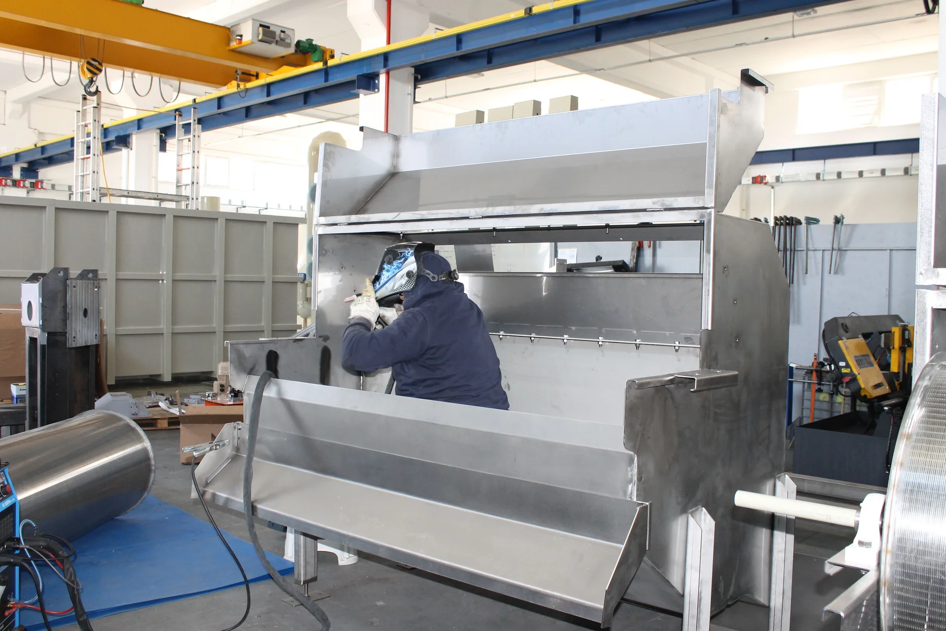 Welder fabricating a stainless steel unit in a workshop