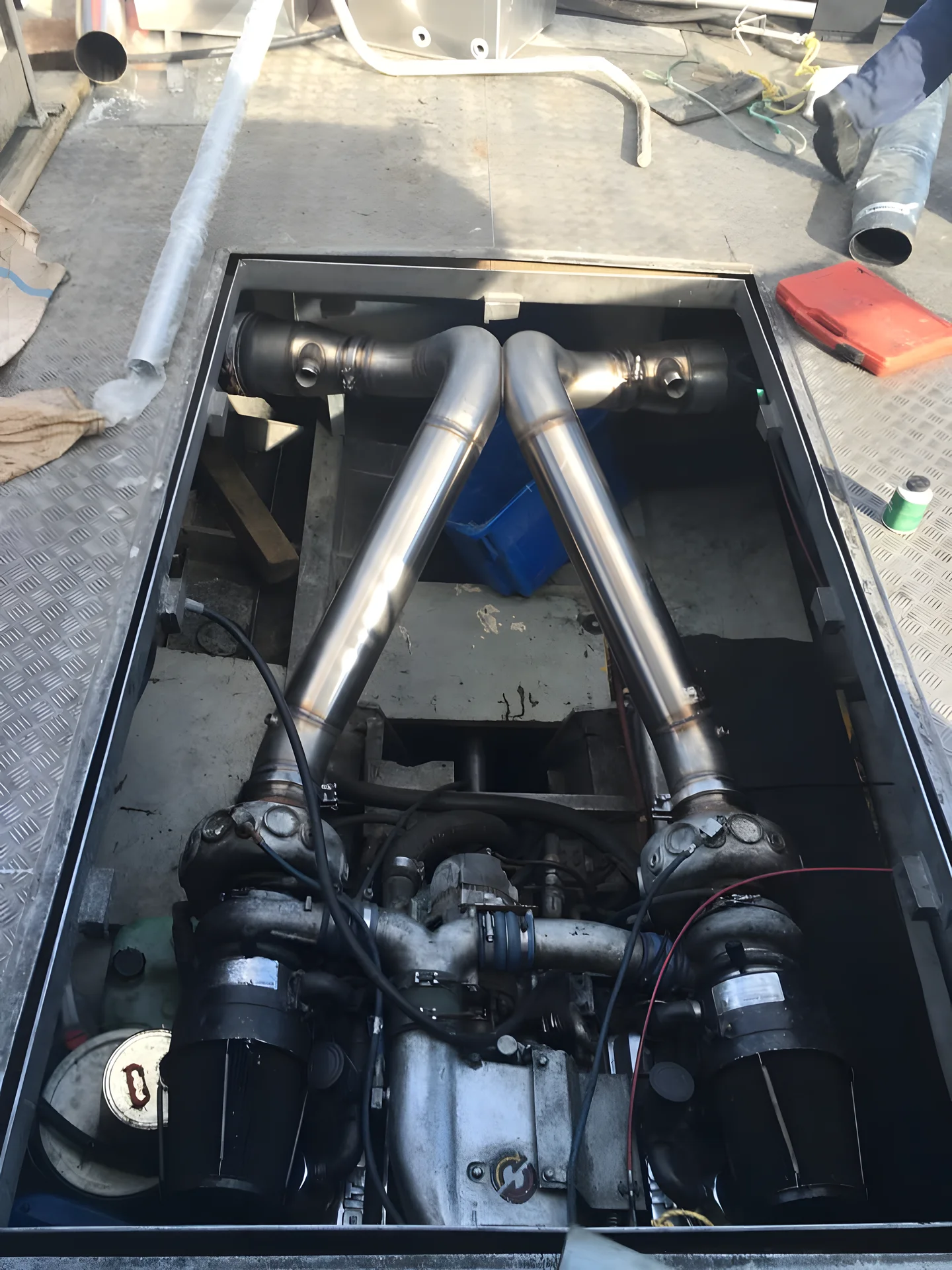 Twin stainless steel exhaust pipes fitted over an engine in an open hatch